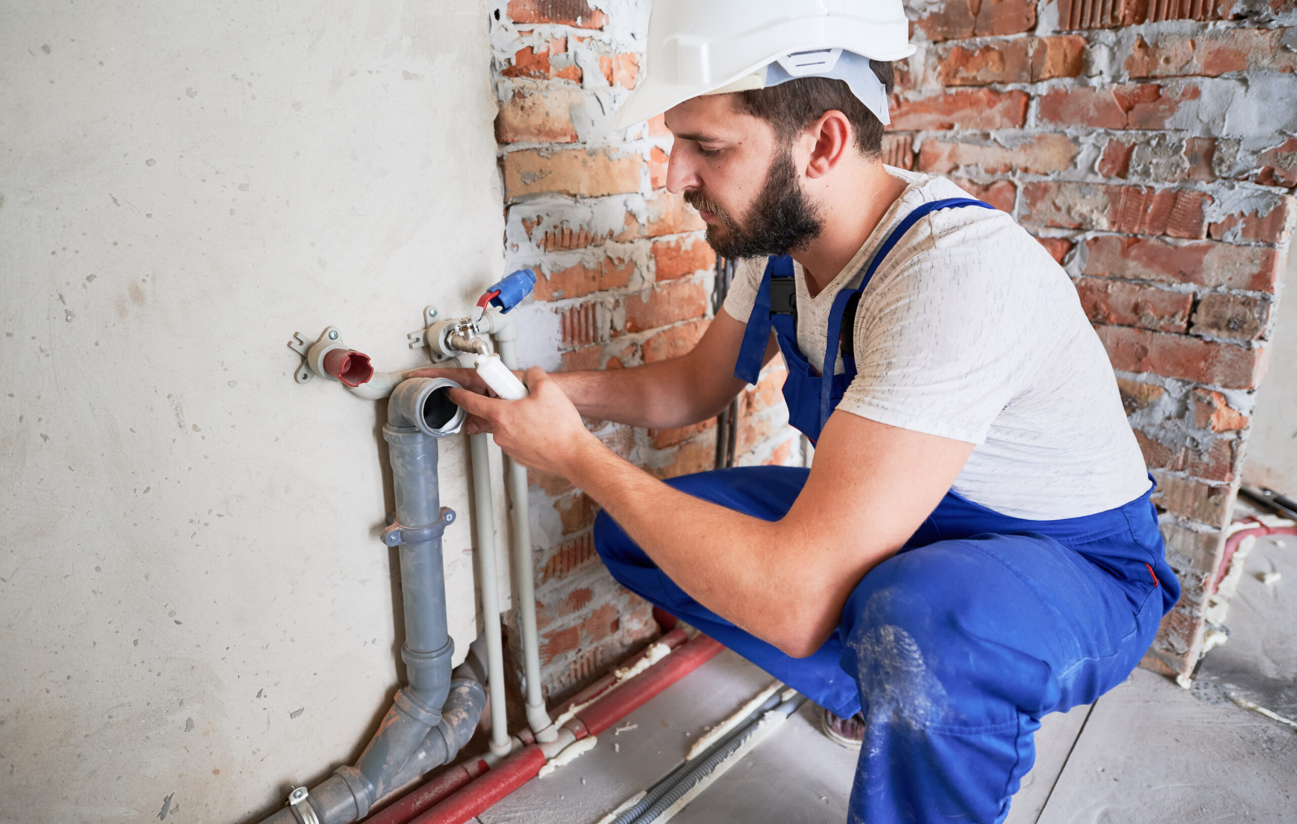 Young plumber working with sealant fix of sewer pipe