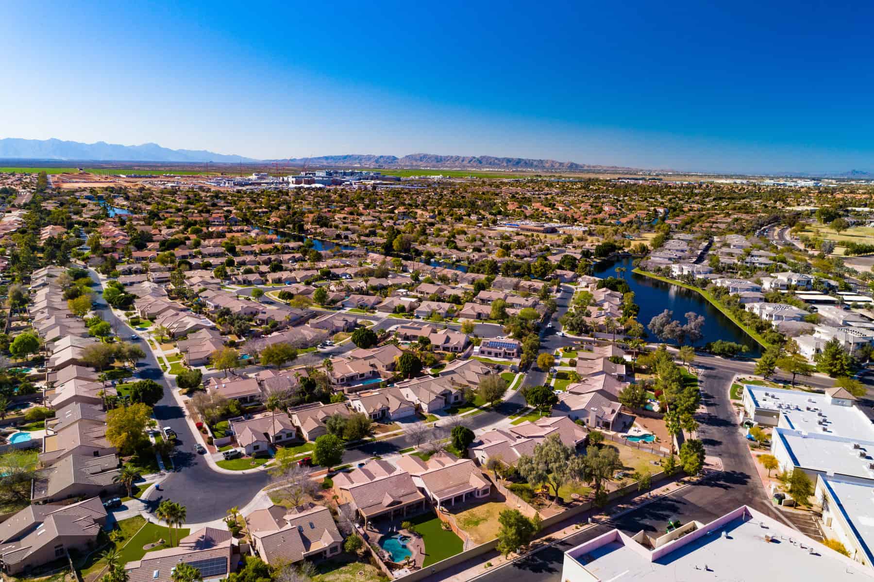 Aerial of residential areas of Chandler, Arizona, with South Mountain and the Sierra Estrella mountain range in the distance.  Chandler is part of the Phoenix Metropolitan Area.