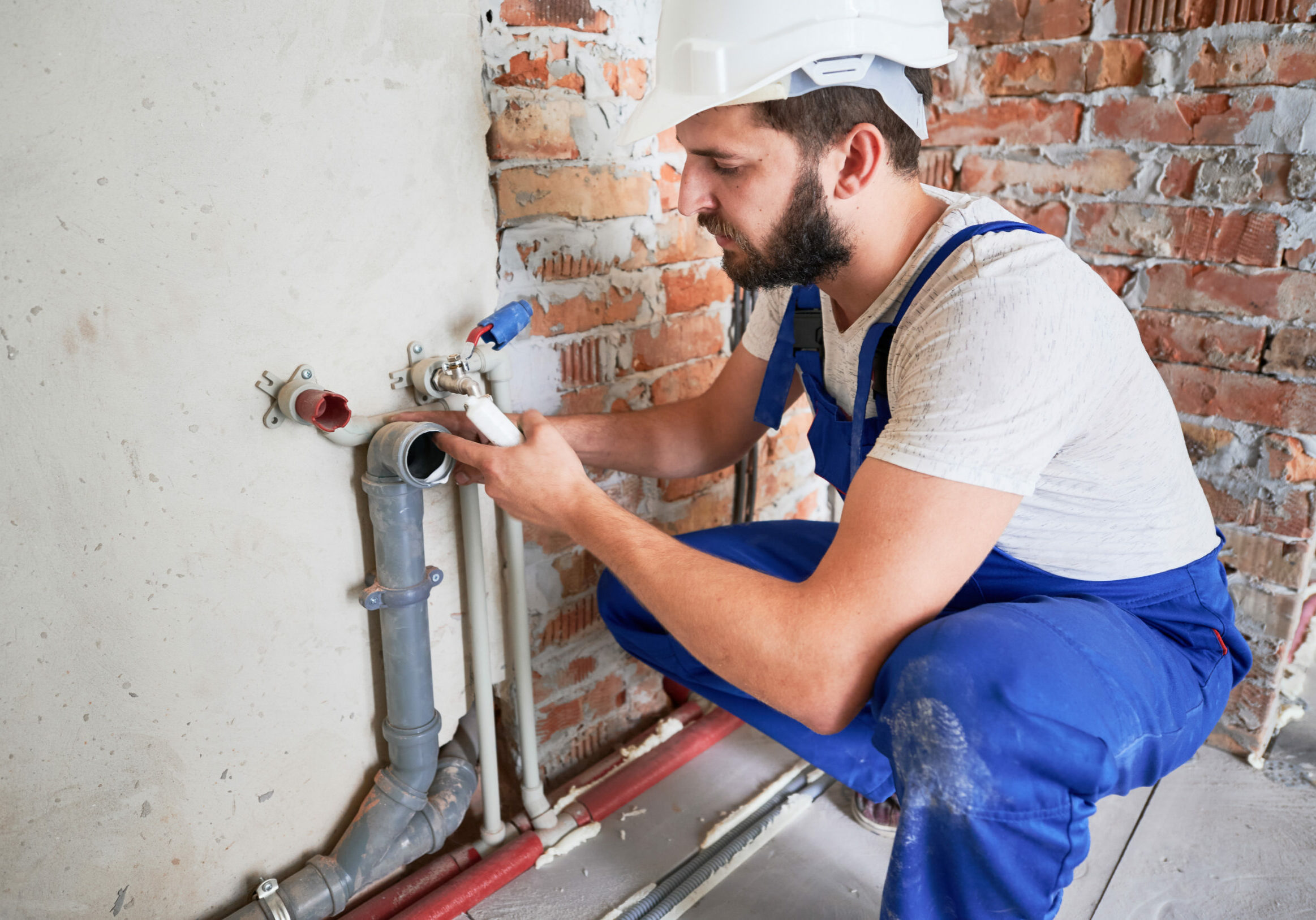 Young plumber working with sealant fix of sewer pipe